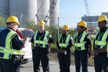 Security team in safety gear receiving instructions at a construction site.