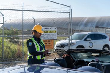 Security officer checks a convertible car at a secure facility entrance.