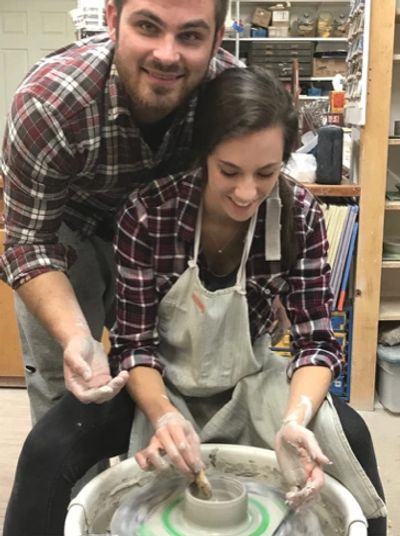 Couple smiling and making pottery on a wheel during an Artyard Studio Couples Date Night class.