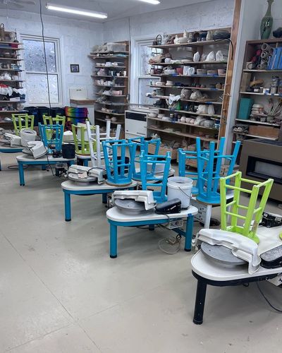 Pottery wheels in a ceramic studio with colorful stools.