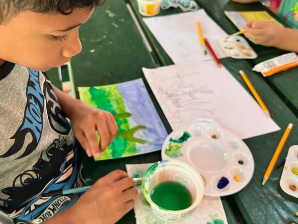 Child painting nature scene outdoors during an Artyard Studio kids summer art camp in WNY