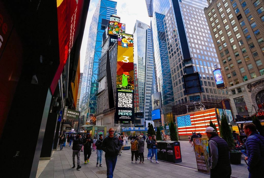 Crowd of people in Times Square with vibrant digital billboards displaying animated characters and promotional content, emphasizing outdoor advertising and brand visibility.