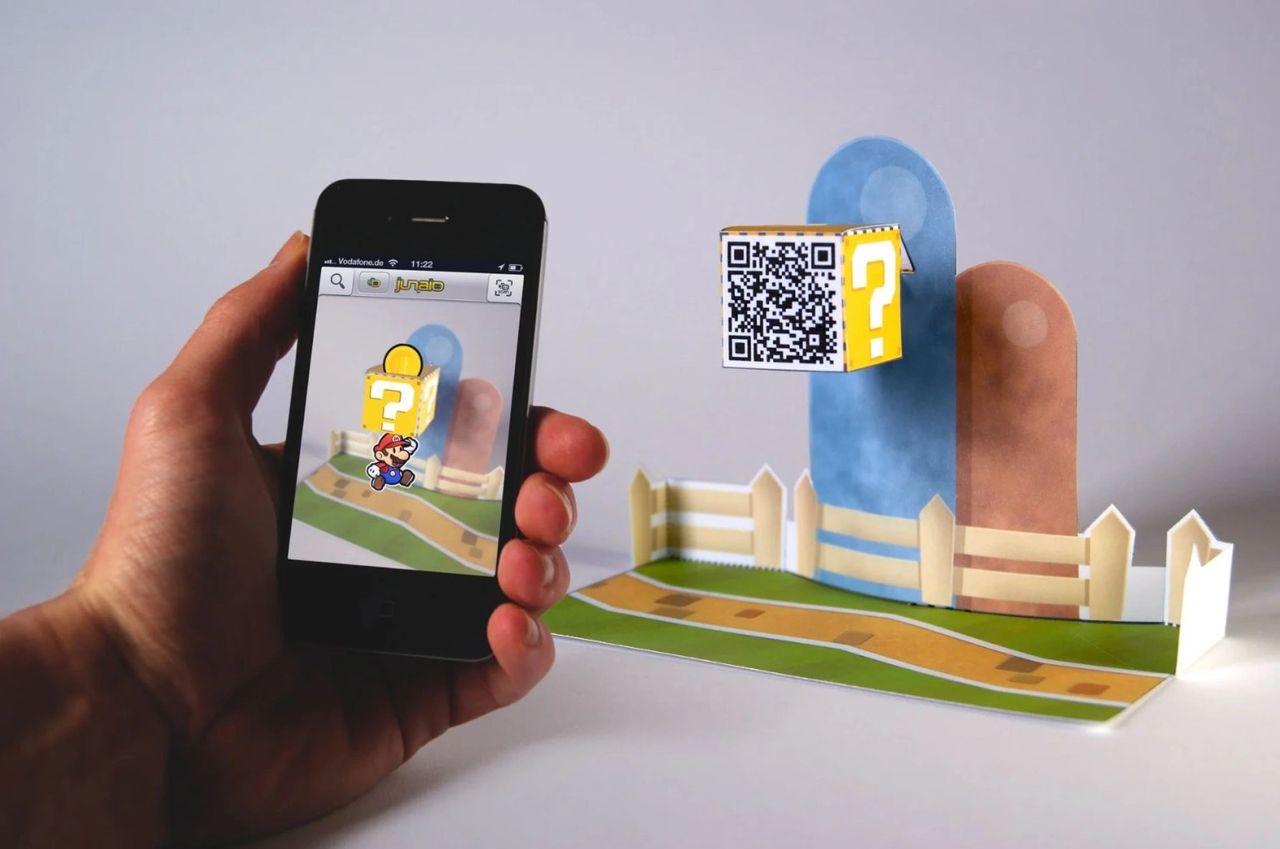 Hand holding smartphone displaying Augmented Reality scene with a question block and character from a video game, emphasizing interactive marketing experiences.