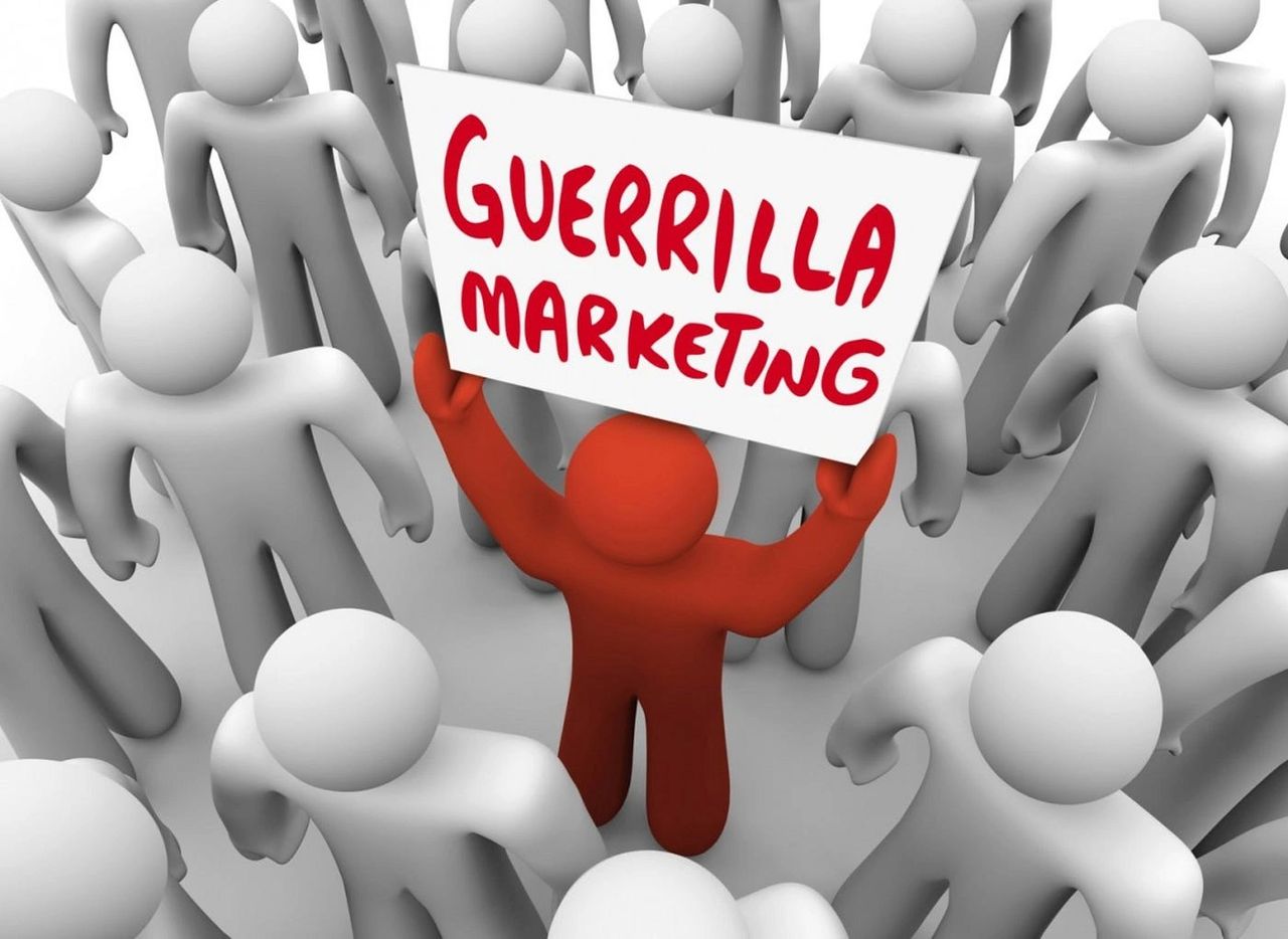 Red figure holding a sign that says "Guerrilla Marketing" surrounded by gray figures, symbolizing innovative marketing strategies in a crowded environment.