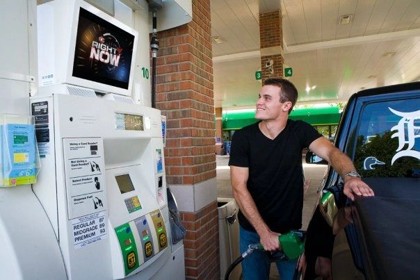 Man fueling a vehicle at a gas station, engaging with a digital screen displaying "RIGHT NOW," highlighting the effectiveness of gas pump TV advertising for brand exposure and audience engagement.