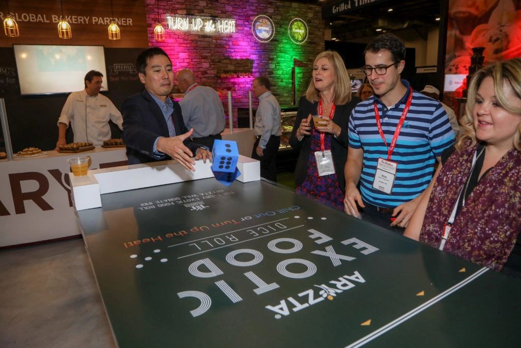 Attendees engaging in interactive food game at Aryzta's trade show booth, showcasing personalized interactions and enhancing brand visibility.