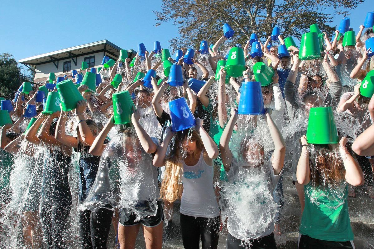 Group of participants pouring water over themselves with colorful buckets, illustrating a viral challenge related to social media engagement and community involvement.