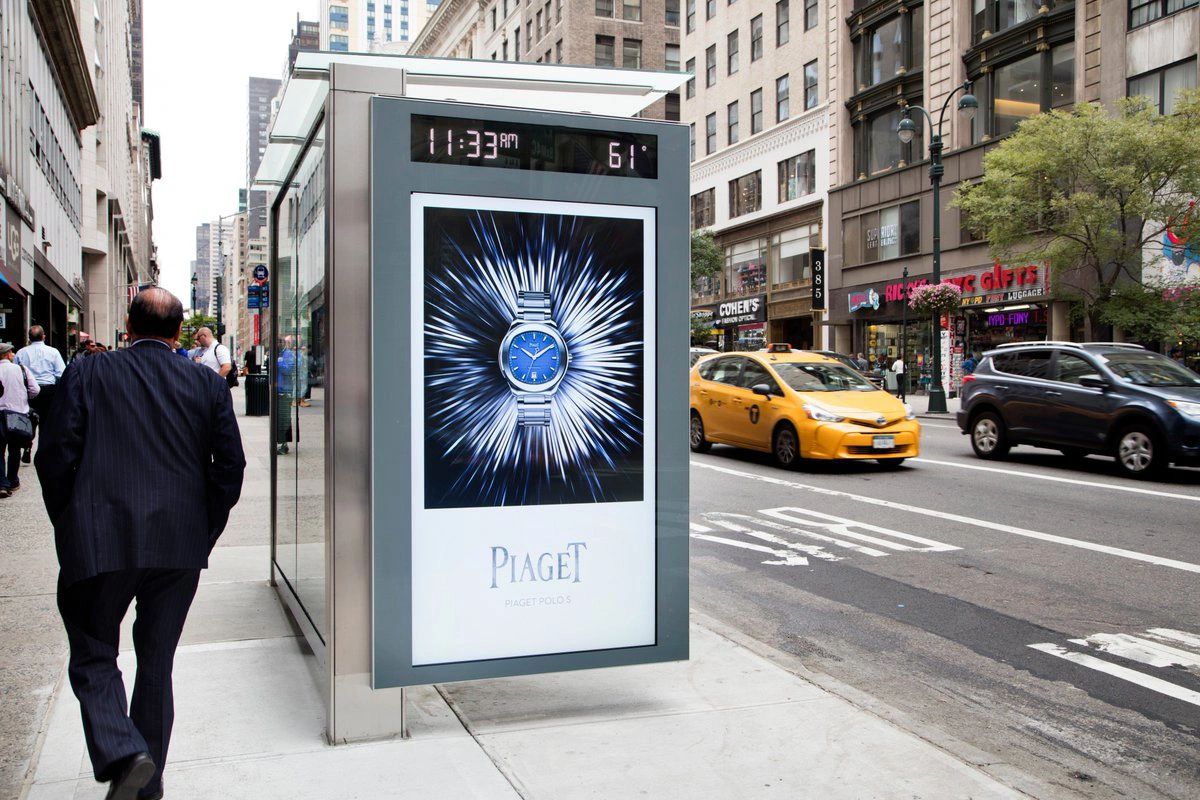 Bus shelter advertisement featuring a Piaget Polo S watch with a striking blue dial, surrounded by dynamic burst graphics, capturing the attention of pedestrians in an urban setting.