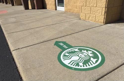 Sidewalk decal featuring Starbucks logo and directional arrow indicating "200 feet," illustrating urban marketing and artistic expression in public spaces.