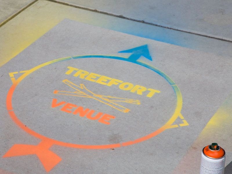 Custom sidewalk stencil designs offer an innovative way to build strong local community relationships and enhance brand presence. Colorful sidewalk stencil featuring "TREEFORT VENUE" and directional arrows, promoting community engagement and local events.