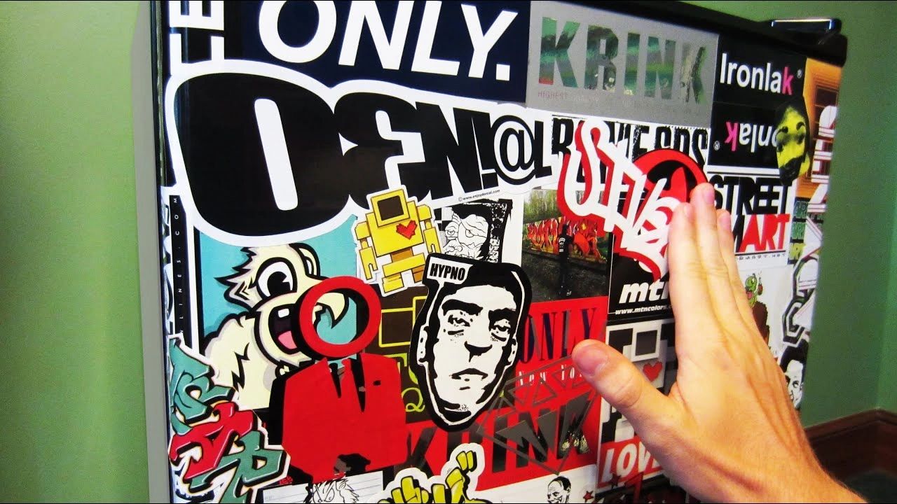 Hand reaching towards a collage of vibrant urban stickers, showcasing various artistic designs and logos, reflecting the creative expression of sticker bombing and guerrilla marketing in urban environments.