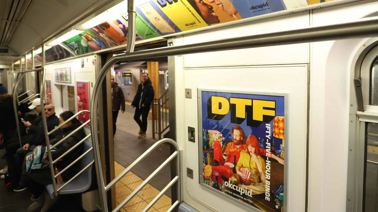 Subway interior featuring vibrant OkCupid advertisement with "DTF" prominently displayed, surrounded by commuters and colorful fashion imagery, reflecting innovative subway advertising strategies.