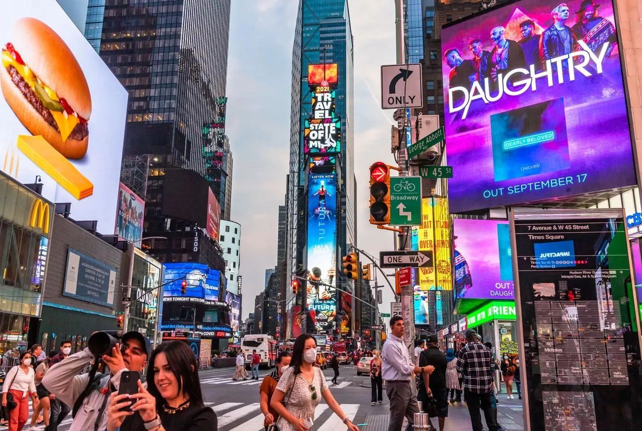 Crowd in Times Square with vibrant advertisements, featuring a McDonald's burger and a Daughtry concert promotion, capturing the essence of urban marketing strategies and consumer engagement.