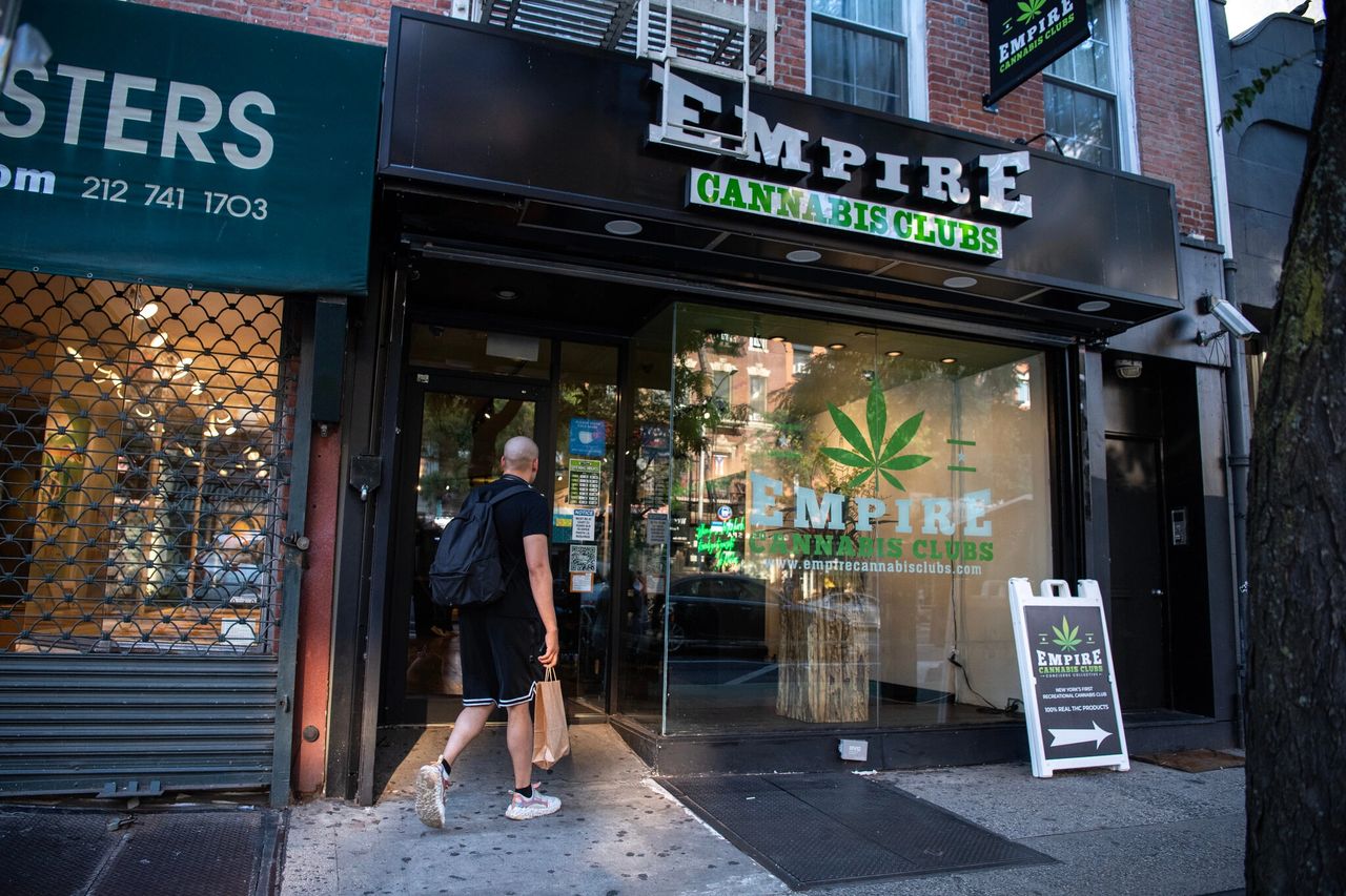 Man entering Empire Cannabis Club storefront in New York City, showcasing cannabis promotion and compliance with local regulations.
