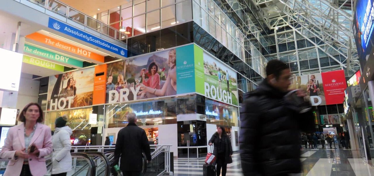 Advertising in malls can provide your business with increased exposure, allowing you to reach a wider audience. Mall interior featuring vibrant advertising banners promoting Scottsdale tourism, with shoppers walking by, emphasizing effective mall advertising strategies.