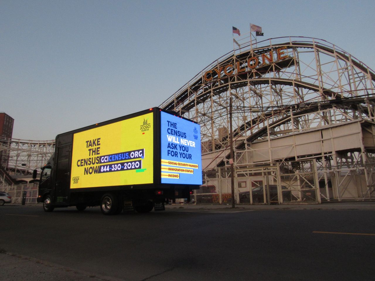 LED mobile billboard truck promoting census awareness, displaying "Take the Census Now" and contact information, with Coney Island's Cyclone roller coaster in the background, emphasizing urban advertising effectiveness.