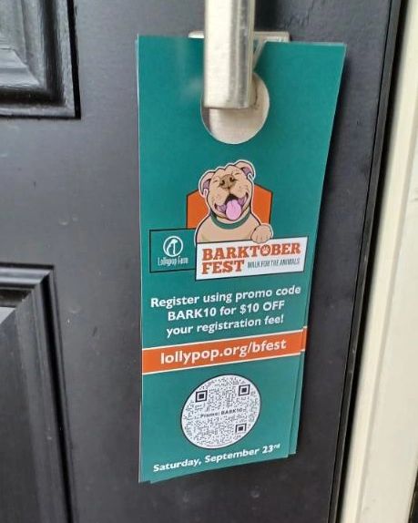 Door hanger promoting Barktober Fest event, featuring a dog illustration, registration details, promo code BARK10 for discount, and a QR code for more information.