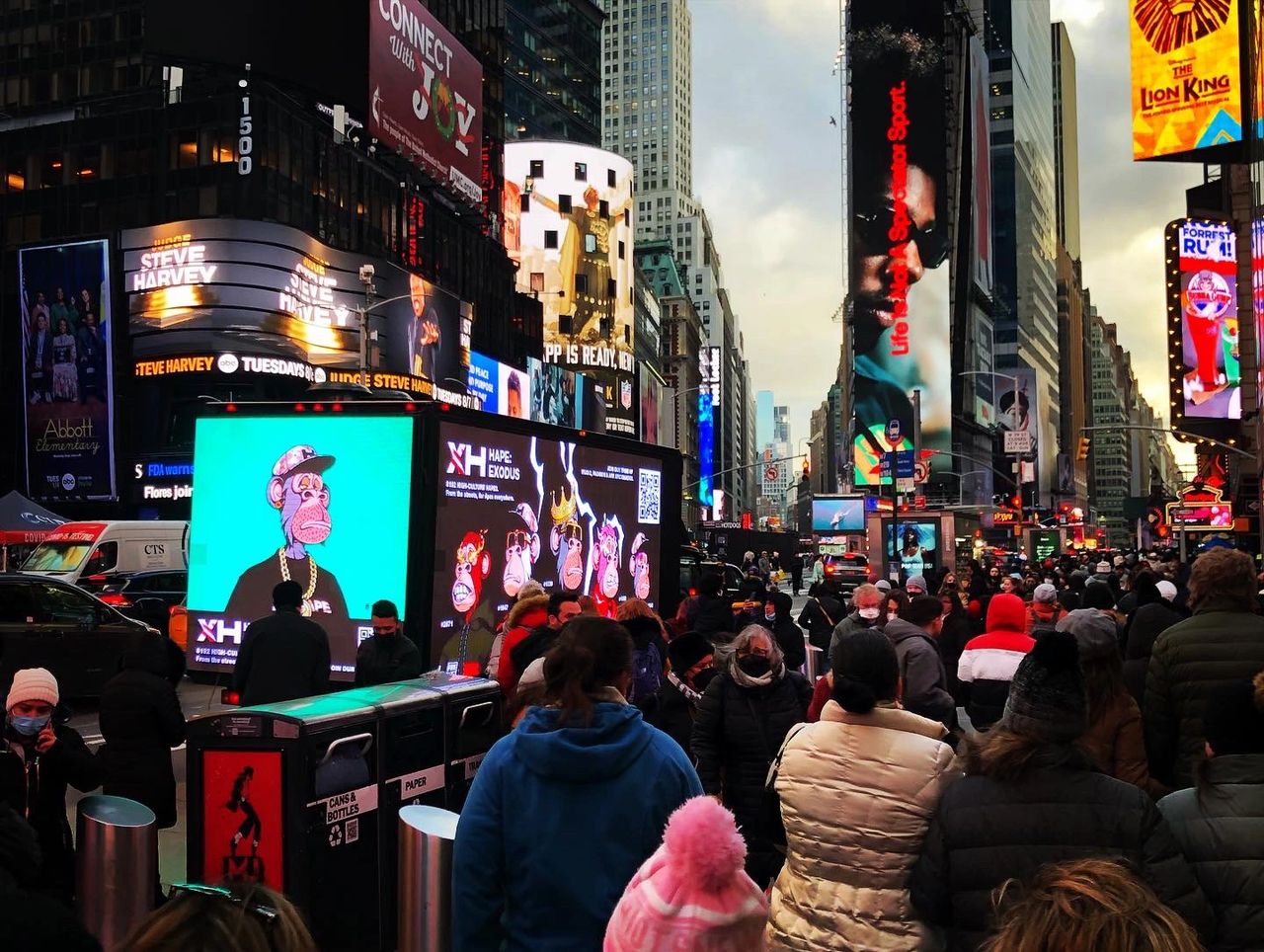 Crowd in Times Square with vibrant digital ads featuring cartoon characters and celebrity promotions, showcasing guerrilla marketing tactics in a bustling urban environment.
