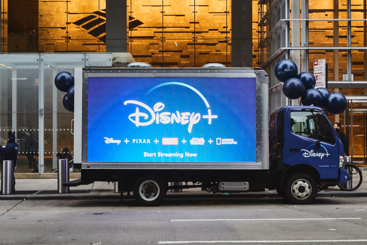 Mobile LED billboard truck promoting Disney+ with branding for Disney, Pixar, Marvel, Star Wars, and National Geographic, featuring the text "Start Streaming Now" and surrounded by black balloons, set in an urban environment.