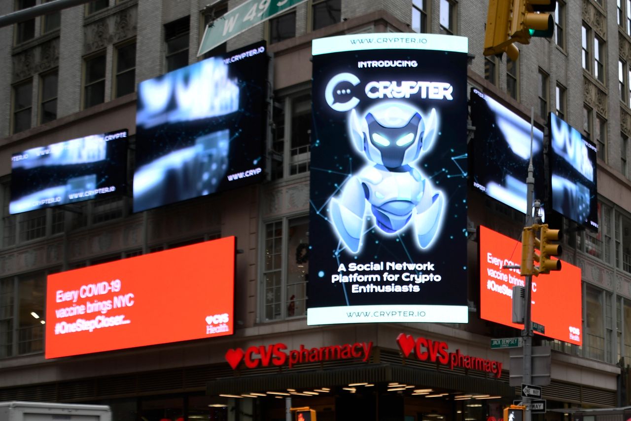 Billboards in Times Square featuring Crypter, a social network platform for crypto enthusiasts, alongside a CVS Health advertisement promoting COVID-19 vaccinations.