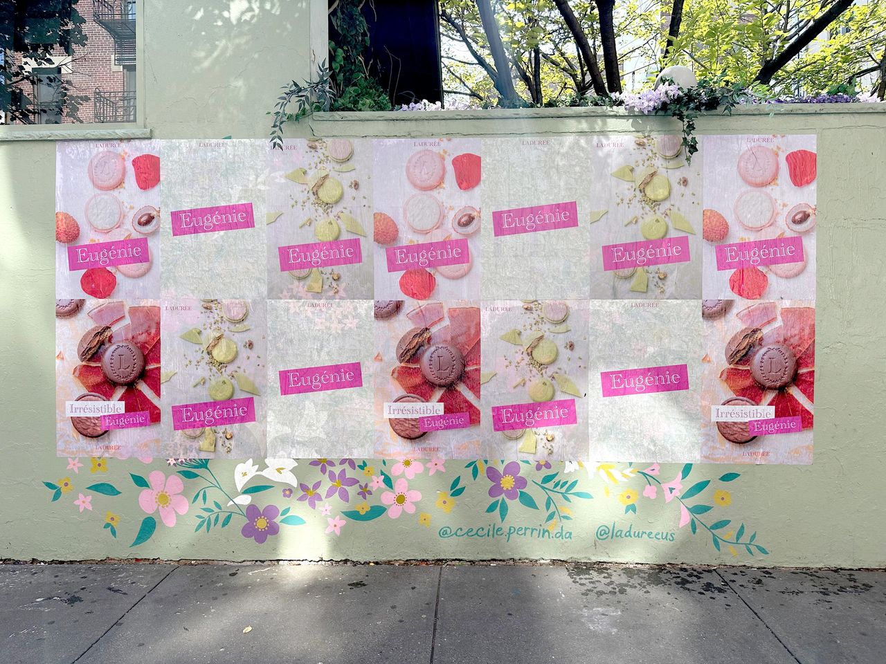 Wheat paste art installation featuring multiple posters of macarons with "Eug&eacute;nie" branding on a green wall, surrounded by floral designs, illustrating street marketing techniques in Los Angeles.