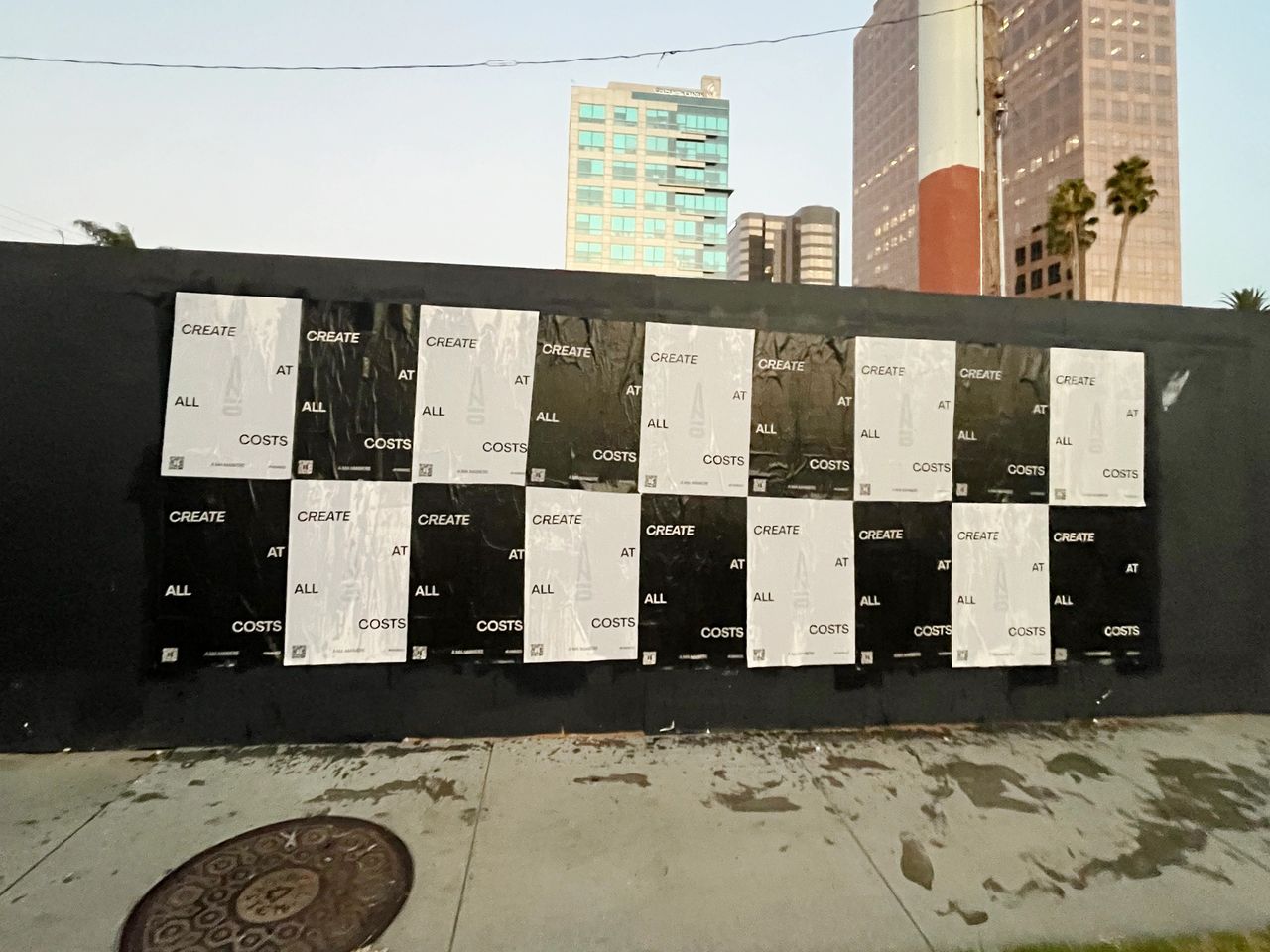 Posters displaying the phrase "CREATE AT ALL COSTS" in a striking black and white design, emphasizing poster marketing strategies in urban settings like Washington.