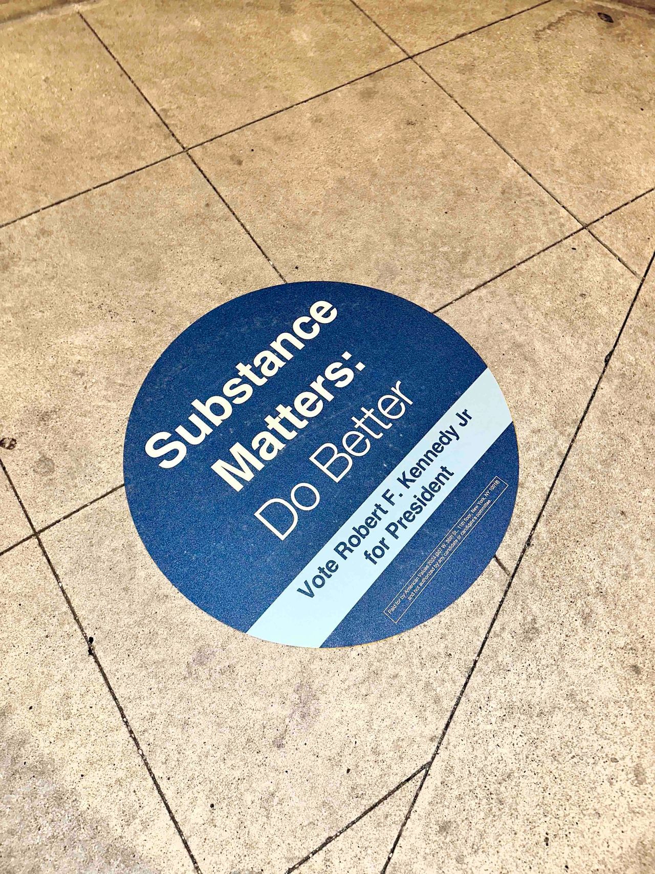 Circular floor graphic promoting Robert F. Kennedy Jr.'s presidential campaign with the text "Substance Matters: Do Better."