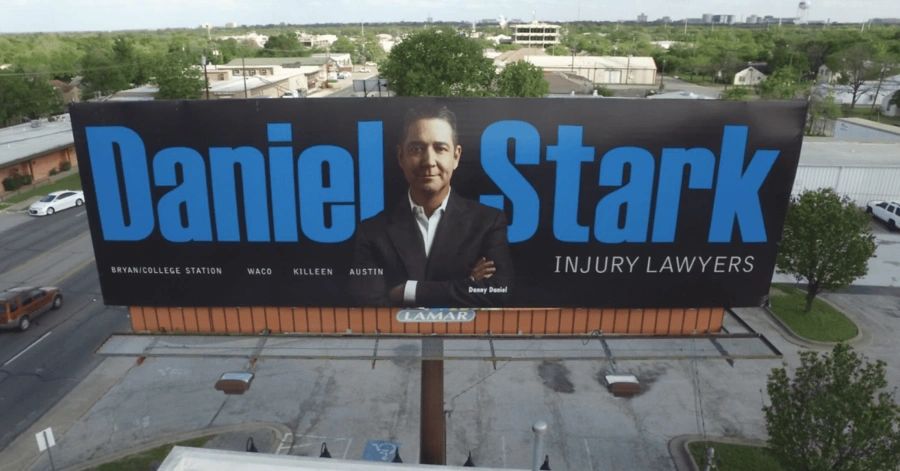 Billboard advertising Daniel Stark Injury Lawyers, featuring a professional portrait of a lawyer, with the text emphasizing the firm's locations: Bryan/College Station, Waco, Killeen, and Austin.