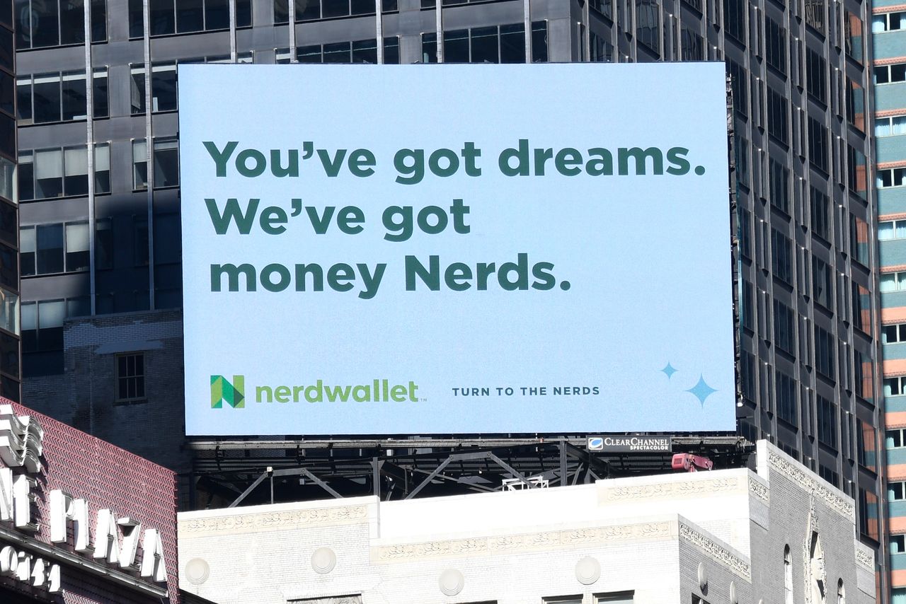 Today's consumers are everywhere Billboard advertisement featuring the text "You’ve got dreams. We’ve got money Nerds." promoting NerdWallet, set against a cityscape backdrop.