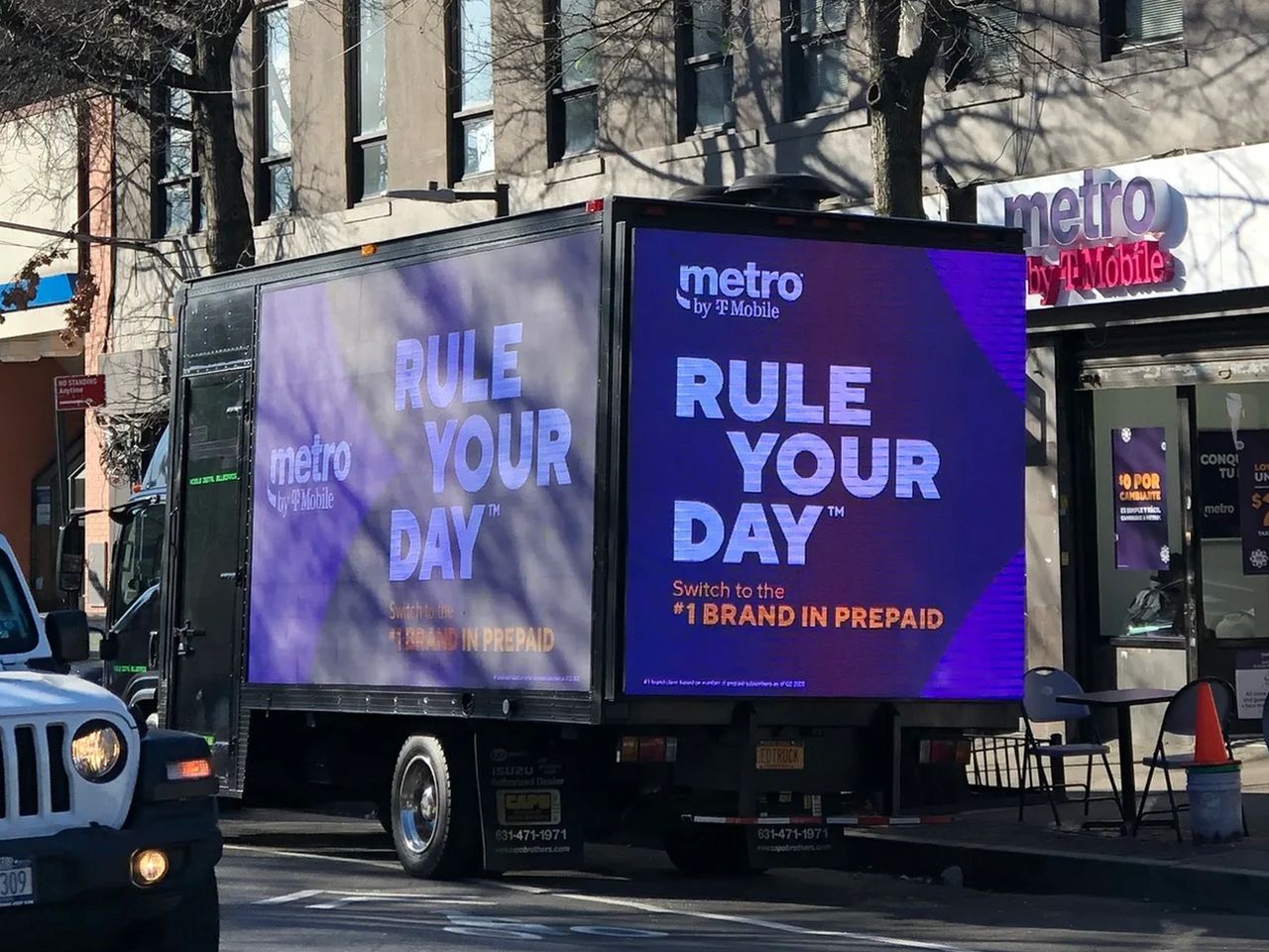 Mobile billboard advertising "Rule Your Day" by Metro by T-Mobile, featuring vibrant graphics and promotional text, situated in an urban environment.
