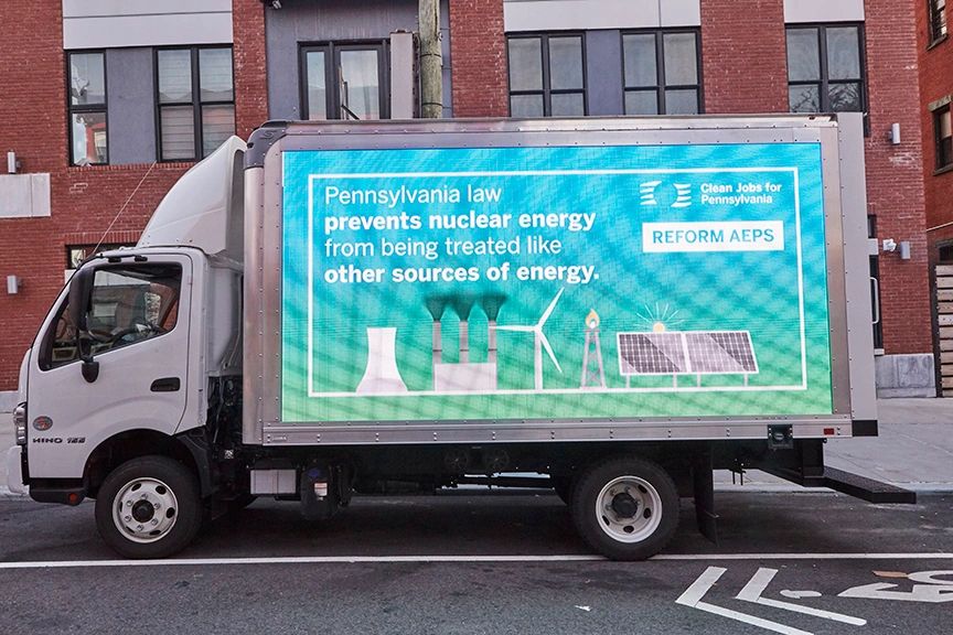 LED billboard truck displaying message about Pennsylvania law preventing nuclear energy from being treated like other energy sources, featuring graphics of energy sources and the call to "Reform AEPS."