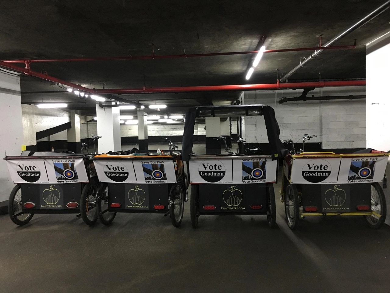 Pedicabs with "Vote Goodman" banners parked in an underground area, promoting eco-friendly transportation and local political engagement.