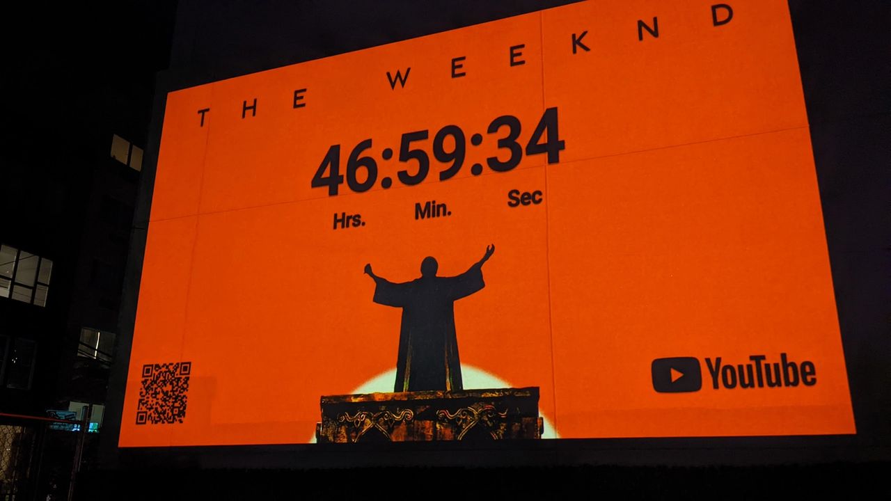 Projection advertising for The Weeknd featuring a countdown timer on an orange background, showcasing the artist's silhouette and a QR code, emphasizing innovative street advertising techniques in Nashville, TN.