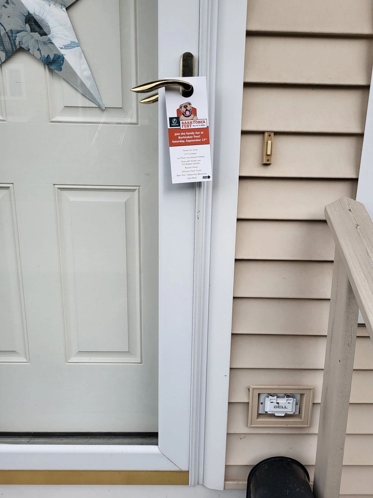 Door hanger advertising for Barktober Fest event, featuring details about family-friendly activities, displayed on a residential door.