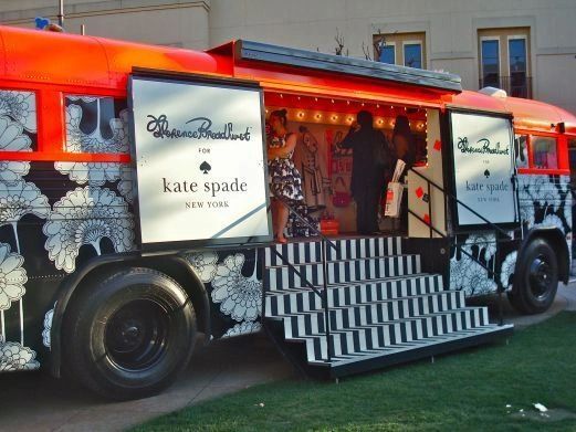 Mobile pop-up shop for Kate Spade featuring a decorated bus with black and white floral design, showcasing a vibrant retail space and steps leading up to the entrance.