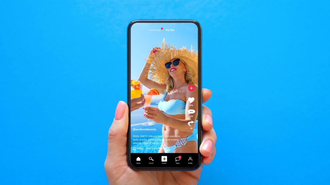 Hand holding smartphone displaying vibrant TikTok video of a woman in a blue bikini enjoying cocktails at a pool party, emphasizing influencer marketing and engagement strategies for small businesses.