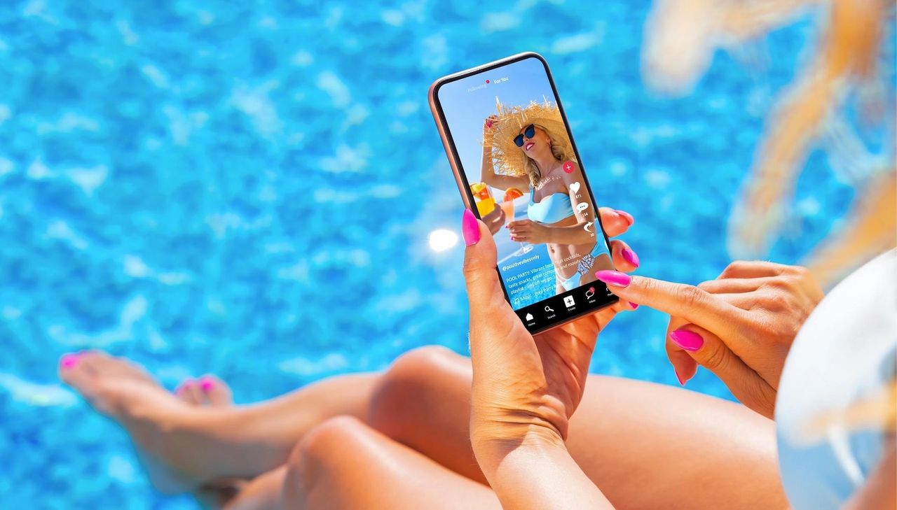 Person holding smartphone displaying TikTok video, featuring summer pool scene and vibrant content, emphasizing TikTok advertising for small businesses.