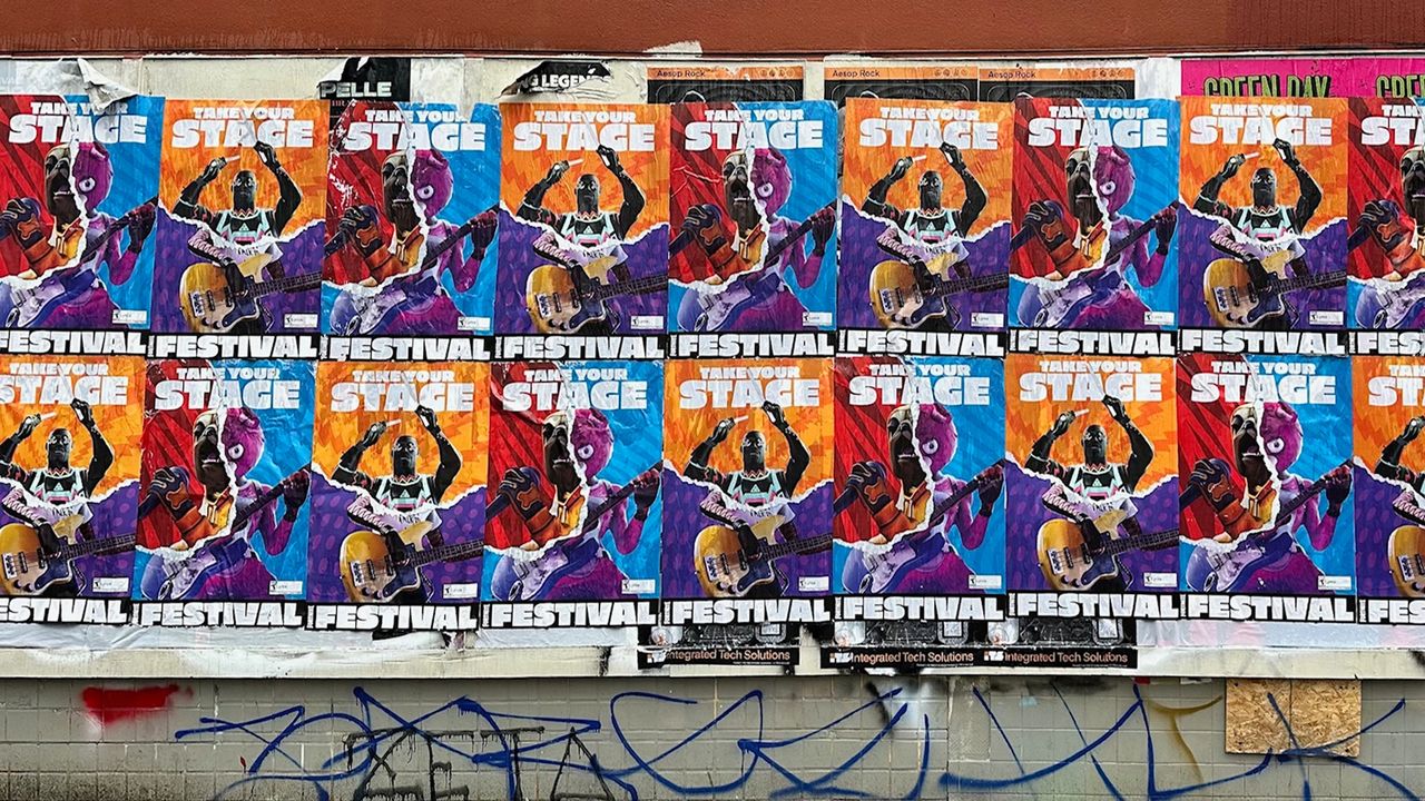 Colorful wheatpaste posters promoting a music festival, featuring vibrant graphics of a guitarist and bold text "Take Your Stage," showcasing guerrilla marketing in urban street advertising.