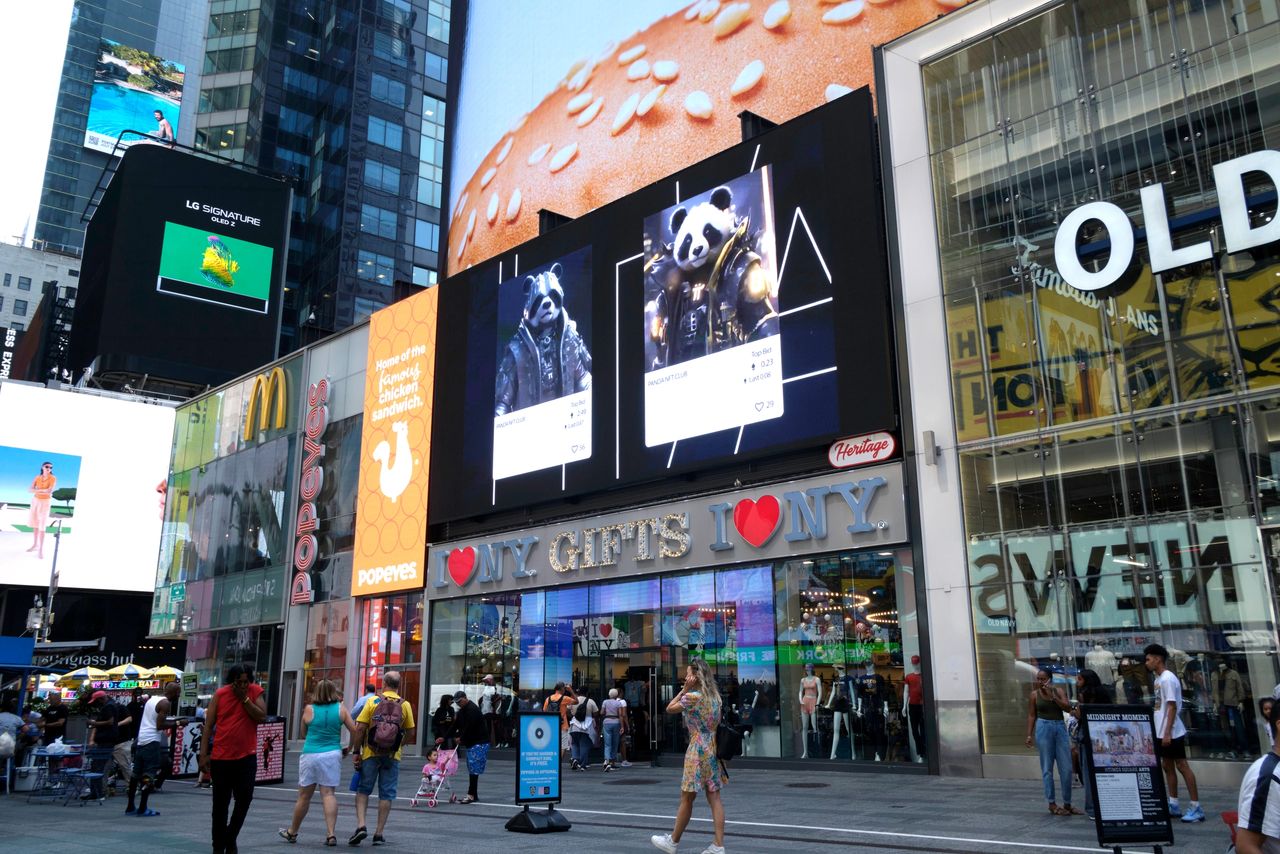 Billboards in Times Square displaying vibrant advertisements, including LG and a panda-themed promotion, with crowds of pedestrians and the "I ❤️ NY" gift shop in the foreground.