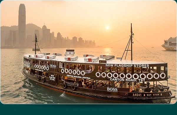 Ferry boat featuring prominent advertisements for Boss, showcasing a scenic sunset over a city skyline, emphasizing innovative ferry advertising in New York.
