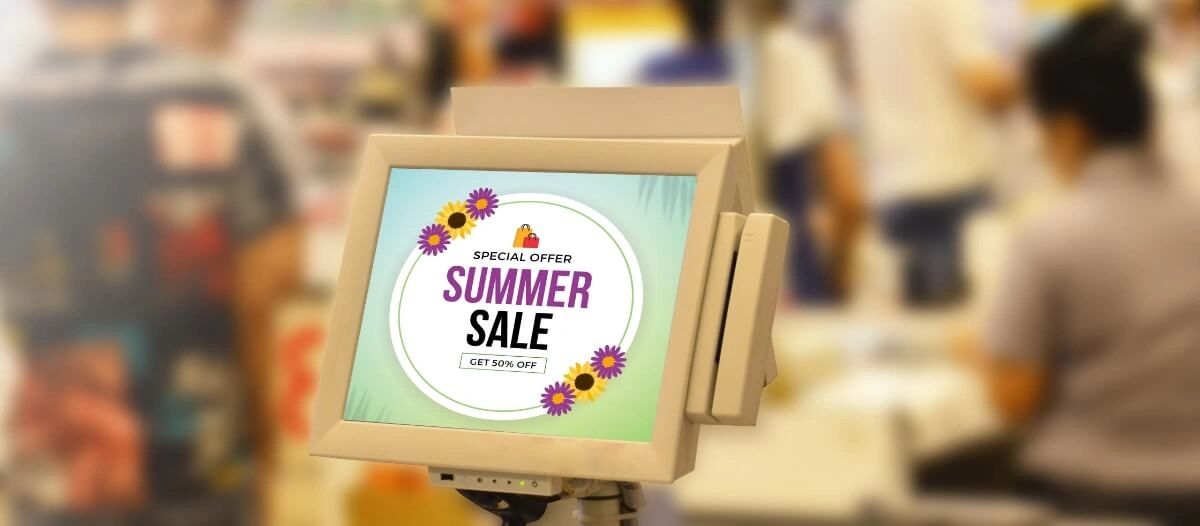 Point of sale advertising display featuring "Summer Sale" promotion with 50% off, surrounded by blurred shoppers in a retail environment.