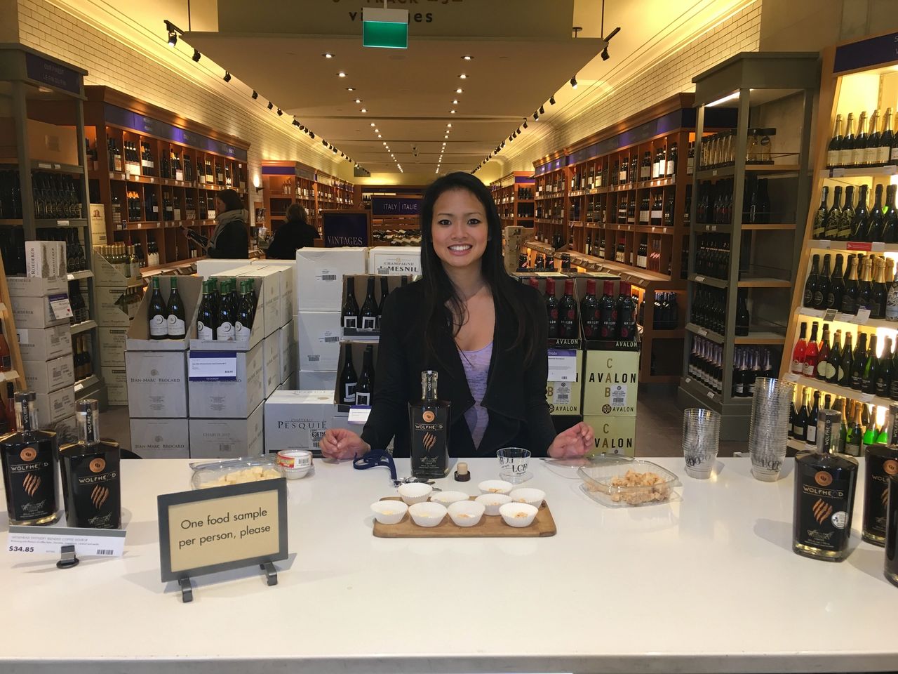 Sampling staff member presenting Wolffer Estate products with food samples at a wine retail store, enhancing customer engagement and brand loyalty.