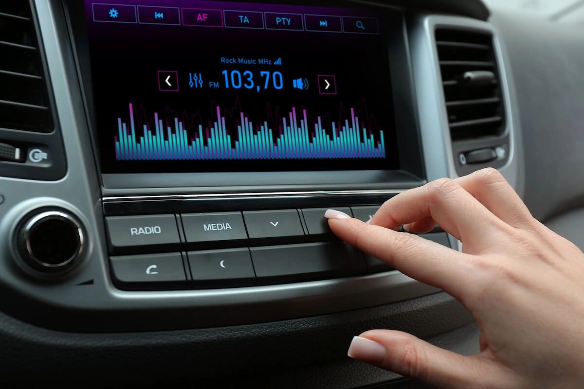 Comparing the cost per impression between radio advertising and other mediums reveals its affordability in reaching a large audience. With flexible budget options, advertisers can capitalize on radio's ability to deliver their message effectively without breaking the bank. Hand adjusting car radio settings, displaying FM station 103.70 and audio visualizer, emphasizing radio's role in effective advertising.
