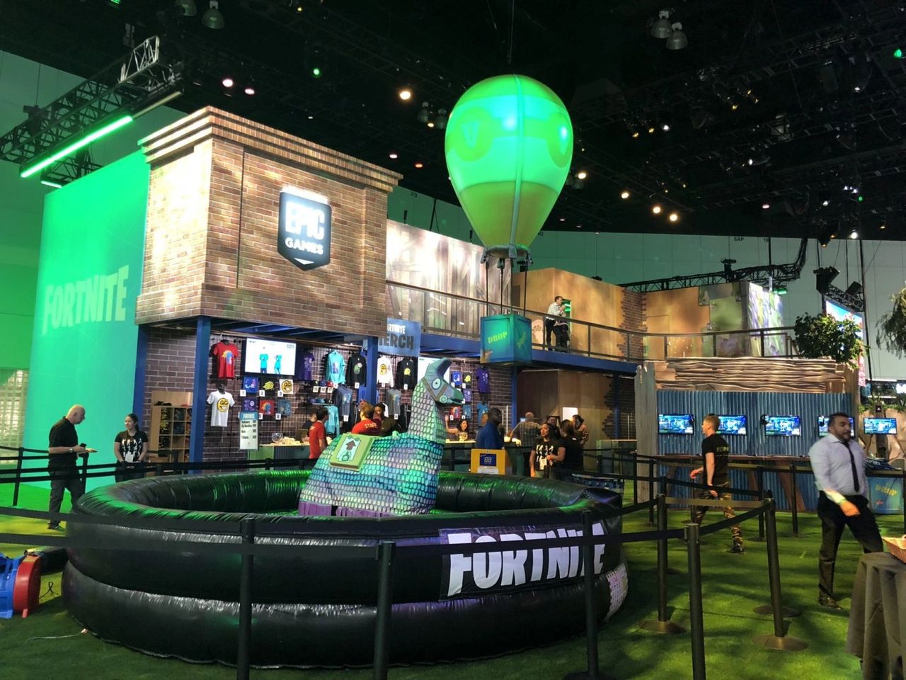 Fortnite-themed trade show booth featuring vibrant branding, merchandise displays, and an inflatable game area, designed to attract attendees and encourage social media sharing.