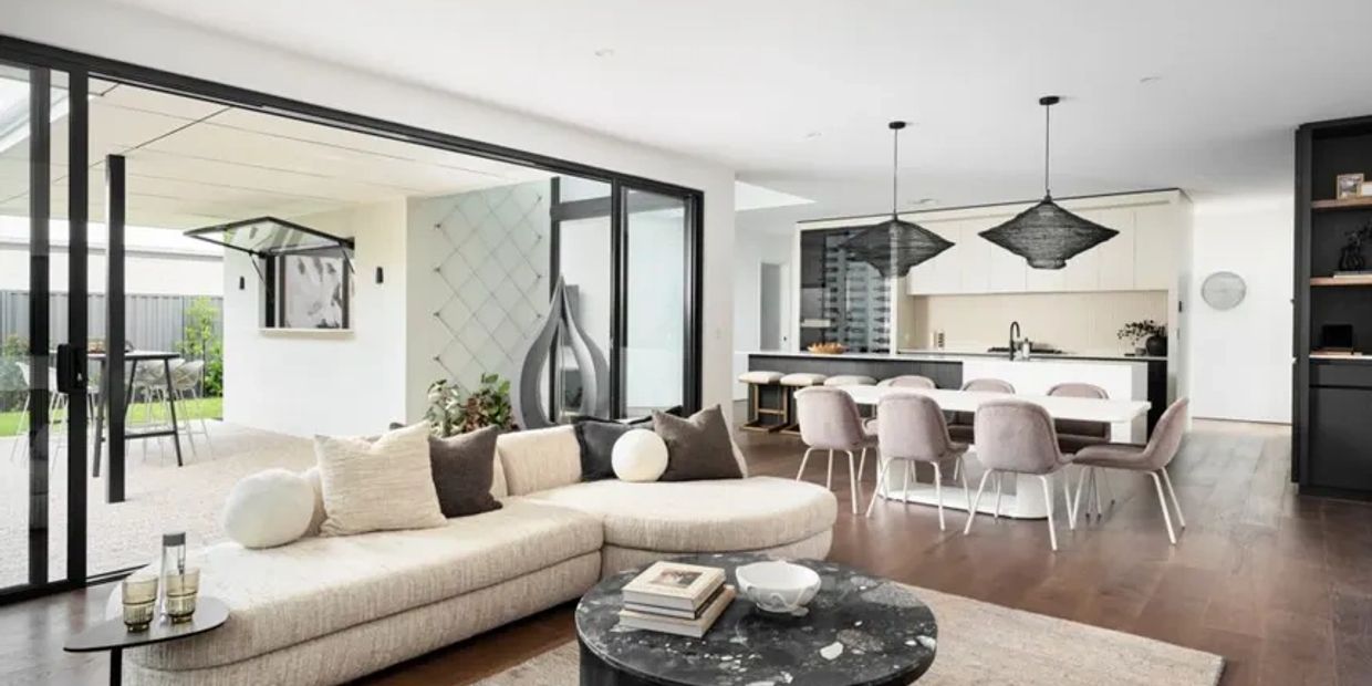 Modern open-plan living room and kitchen with neutral tones and sleek furniture.