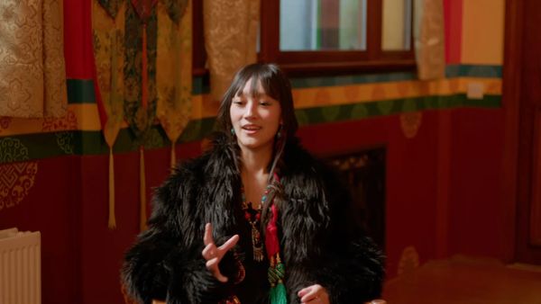 Woman in a dark fur coat talking indoors.