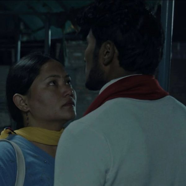 A woman and a man closely facing each other at night.