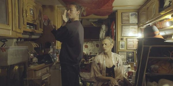 Two people in a cozy, dimly lit room preparing.