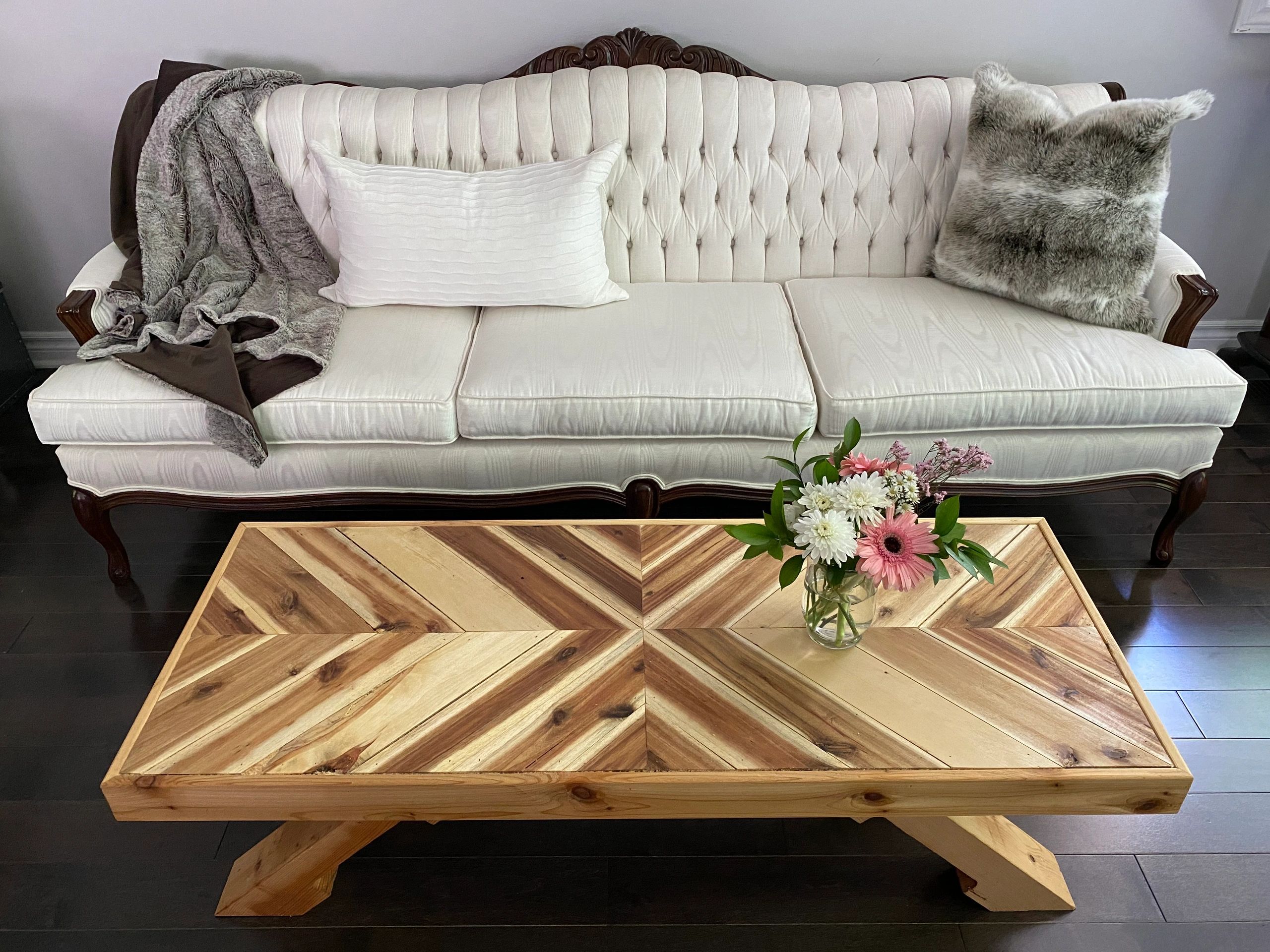 Antique white couch in behind a newly made chevron patterned, multi-toned, coffee table. 