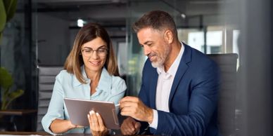 Two colleagues collaborating over a tablet in a modern office.